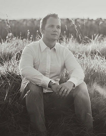 Porträt von Psychotherapeut Alexander Steiner, sitzend, im Hintergrund ein Feld